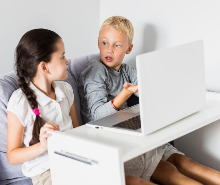 two children sitting in bed watching laptop together